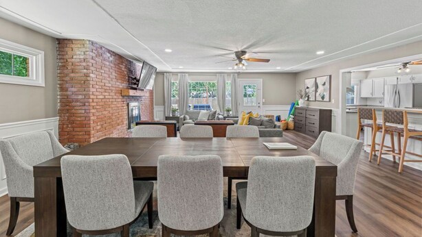 A dining area with a brick accent wall, a ceiling fan, and a view of the kitchen. - Endless Family Entertainment, Fire Pit, 2 Kings! (Wichita)