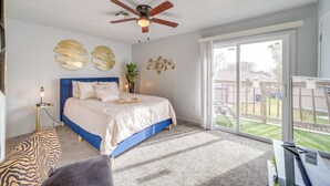 Un dormitorio con cama, ventilador de techo, ventana grande y vistas al exterior.