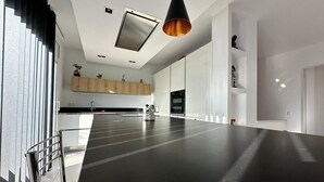 A modern kitchen with a large island, built-in appliances, and a pendant light. - Beautiful Villa Martin AV-88 (Roses)