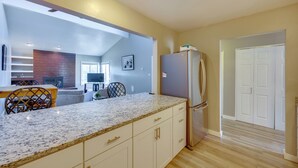 A modern kitchen with a granite countertop, white cabinetry, and a stainless steel refrigerator. - Pet-Friendly Condo w/ Mountain View in Monument! (Monument)