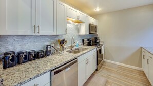 A modern kitchen with white cabinets, granite countertops, a stainless steel dishwasher, and a microwave. - Pet-Friendly Condo w/ Mountain View in Monument! (Monument)