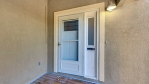 A white door with a frosted glass panel and a "No Soliciting" sign, set in a textured beige wall with a small porch area. - Pet-Friendly Condo w/ Mountain View in Monument! (Monument)
