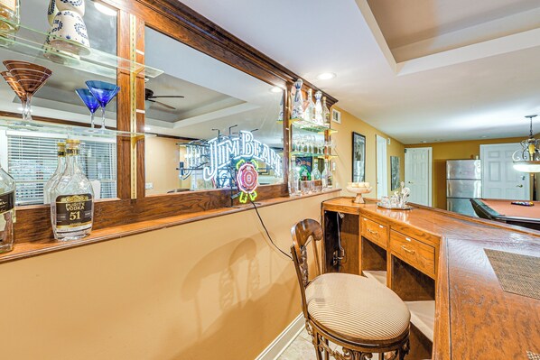 Zona de bar con mostrador de madera, una silla y un letrero de neón.