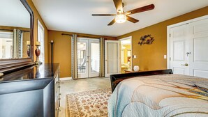 Un dormitorio con cama, cómoda, ventilador de techo y una puerta que da a otra habitación.