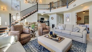 A spacious living area with a staircase, leather armchairs, a sofa, and a coffee table.