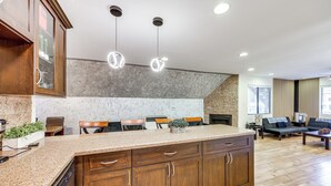 Una cocina con encimeras de granito, armarios de madera e iluminación colgante.