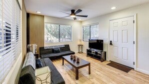 Una sala de estar con sofá, mesa de centro, televisor y una puerta.