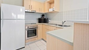 Eine kleine Küche mit Kühlschrank, Mikrowelle, Backofen und Spüle.