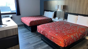 A hotel room with two beds, a desk, and a window.