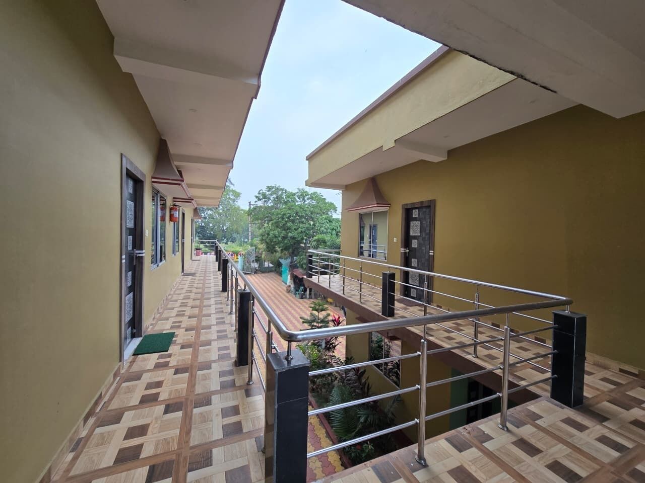 A corridor with a tiled floor leading to a balcony with a metal railing.