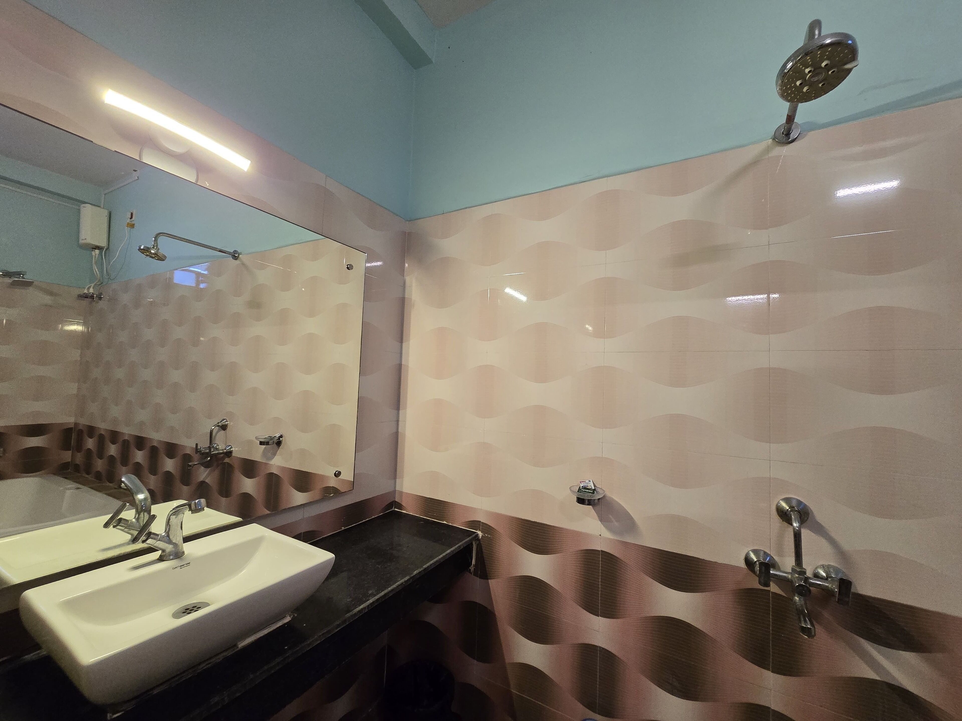 A bathroom with a sink, mirror, and shower.