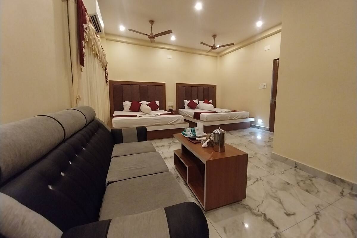 Habitación de hotel con dos camas, un sofá, una mesa de centro y ventiladores de techo.