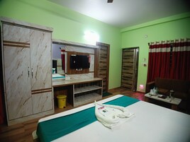 A hotel room with a bed, a wardrobe, a TV, a desk, and a bathroom.