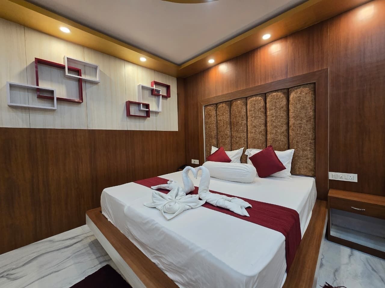 Una habitación de hotel moderna con una cama grande, paneles de madera y estanterías empotradas.