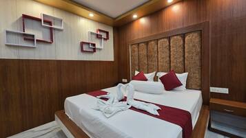 Una habitación de hotel moderna con una cama grande, paneles de madera y estanterías empotradas.