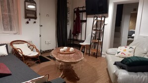 En hyggelig stue med et rundt bord, en sofa, en lænestol og et fjernsyn.