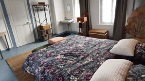 Et soveværelse med en stor seng, et natbord, en stol, et vindue med gardiner og en dør.