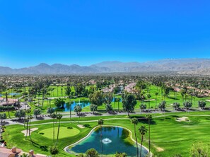A golf course with multiple ponds and palm trees, surrounded by mountains. - 3-Bedroom Condo in Palm Desert – Enjoy Access to Private Golf/Tennis/Pickleball! (Palm Desert)