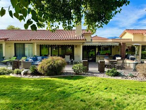 A house with a patio area featuring outdoor furniture, a covered seating area, and a well-maintained lawn. - 3-Bedroom Condo in Palm Desert – Enjoy Access to Private Golf/Tennis/Pickleball! (Palm Desert)