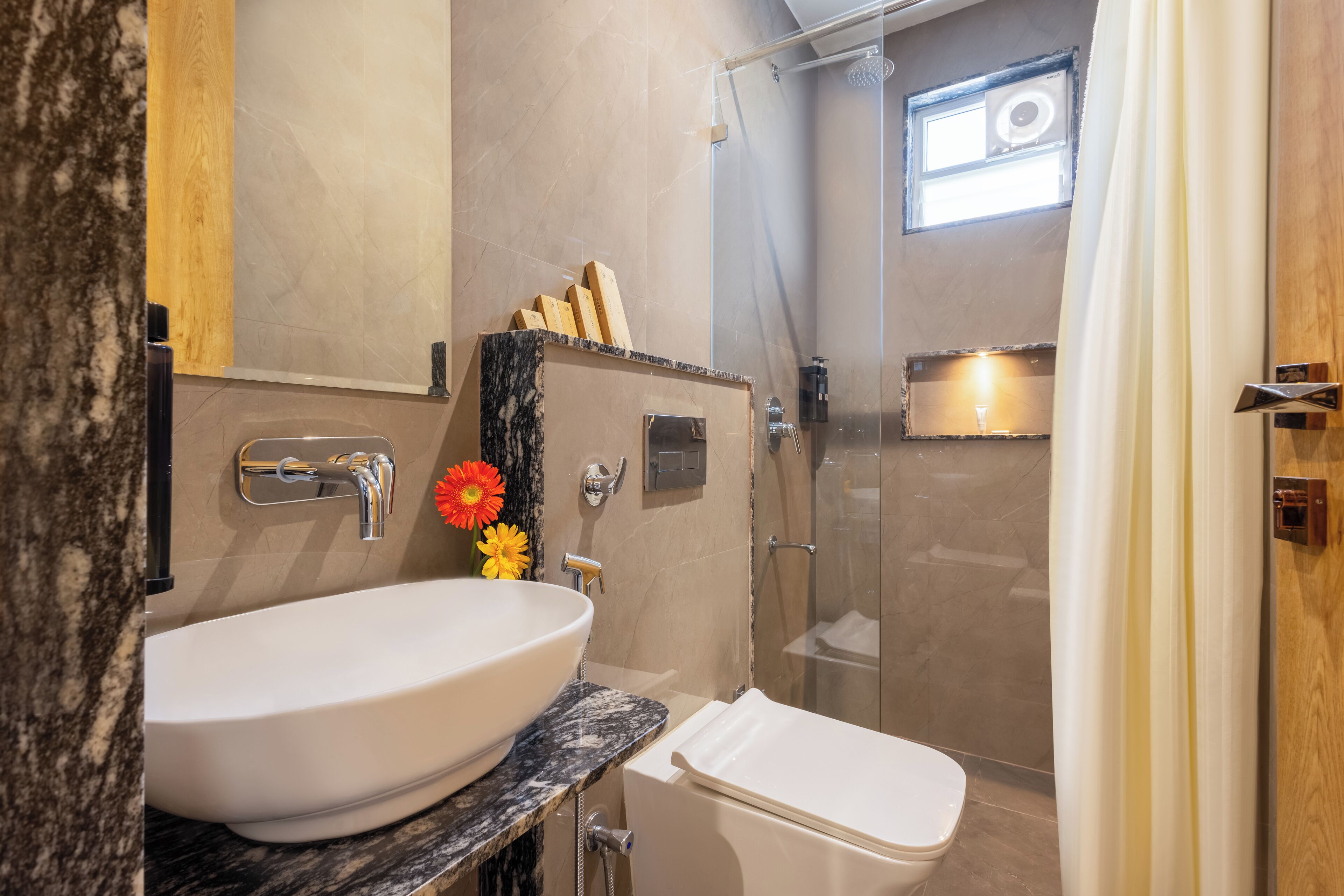 A modern bathroom with a large white sink, a toilet, and a glass-enclosed shower.