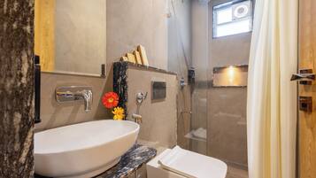 A modern bathroom with a large white sink, a toilet, and a glass-enclosed shower.