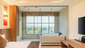 Une chambre d’hôtel moderne avec un grand lit, une baignoire et un téléviseur.