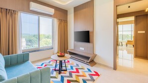 Un salon moderne avec un canapé, un téléviseur fixé au mur et une fenêtre avec des rideaux.
