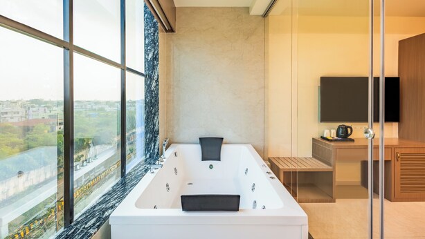 Une salle de bain moderne dotée d’une grande baignoire, d’une douche à parois de verre et offrant une vue sur la ville.