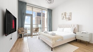 A modern bedroom with a large bed, a flat-screen TV, a chair, and a view of the city through large windows. - Luxury Leisure Massive Pool Oasis (Dubai)