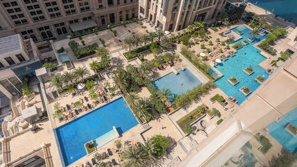 A high-rise hotel with multiple swimming pools, palm trees, and a view of the sea. - Luxury Leisure Massive Pool Oasis (Dubai)