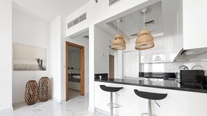 A modern kitchen with white cabinets, black countertops, and two bar stools. - Luxury Leisure Massive Pool Oasis (Dubai)