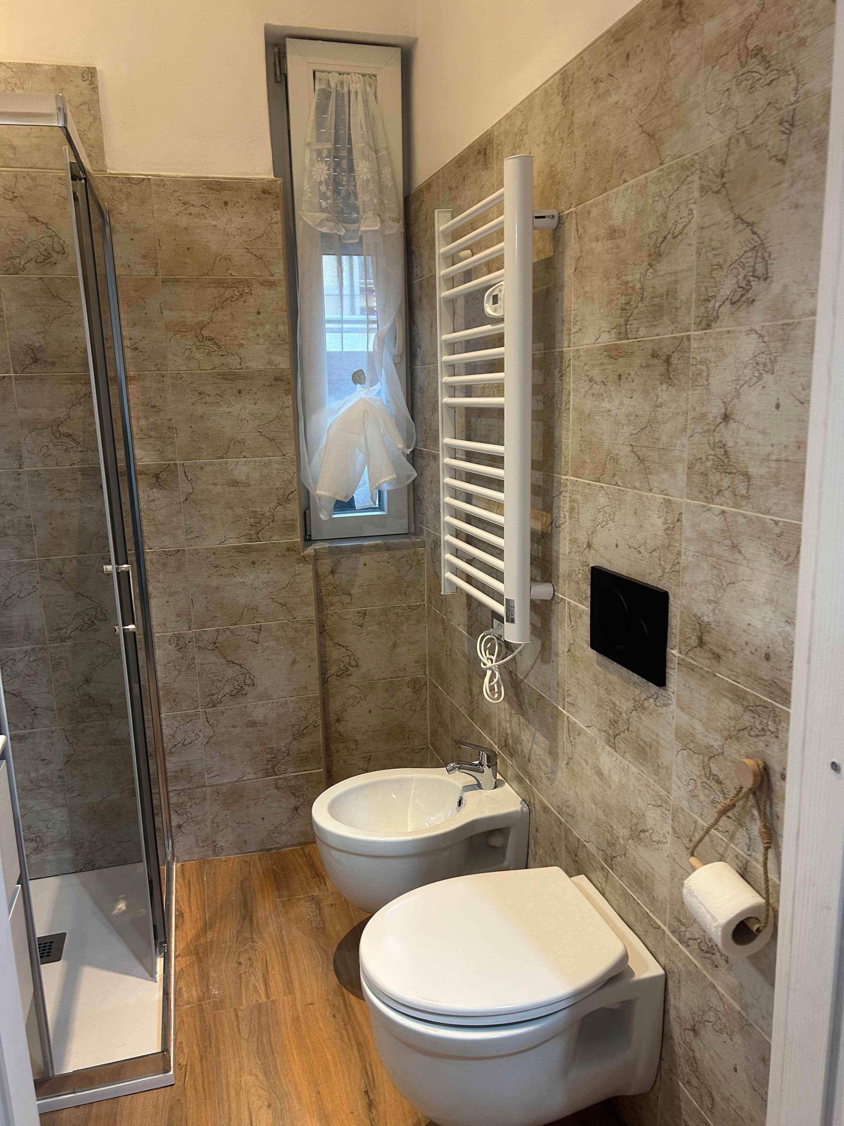 Une salle de bain moderne équipée d’une douche, de deux toilettes, d’un lavabo et d’un porte-serviettes.