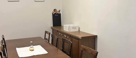 Un comedor con mesa y sillas de madera, una ventana con persianas y aire acondicionado instalado en la pared.