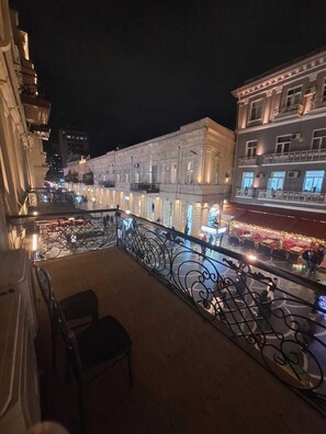 Un balcon doté de rampes en métal ouvragé, donnant sur une rue la nuit.