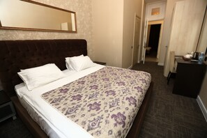 A hotel room with a bed, a bedside table, a dresser, a mirror, and a door leading to another room. - Cosy Hotel Baku (Baku)