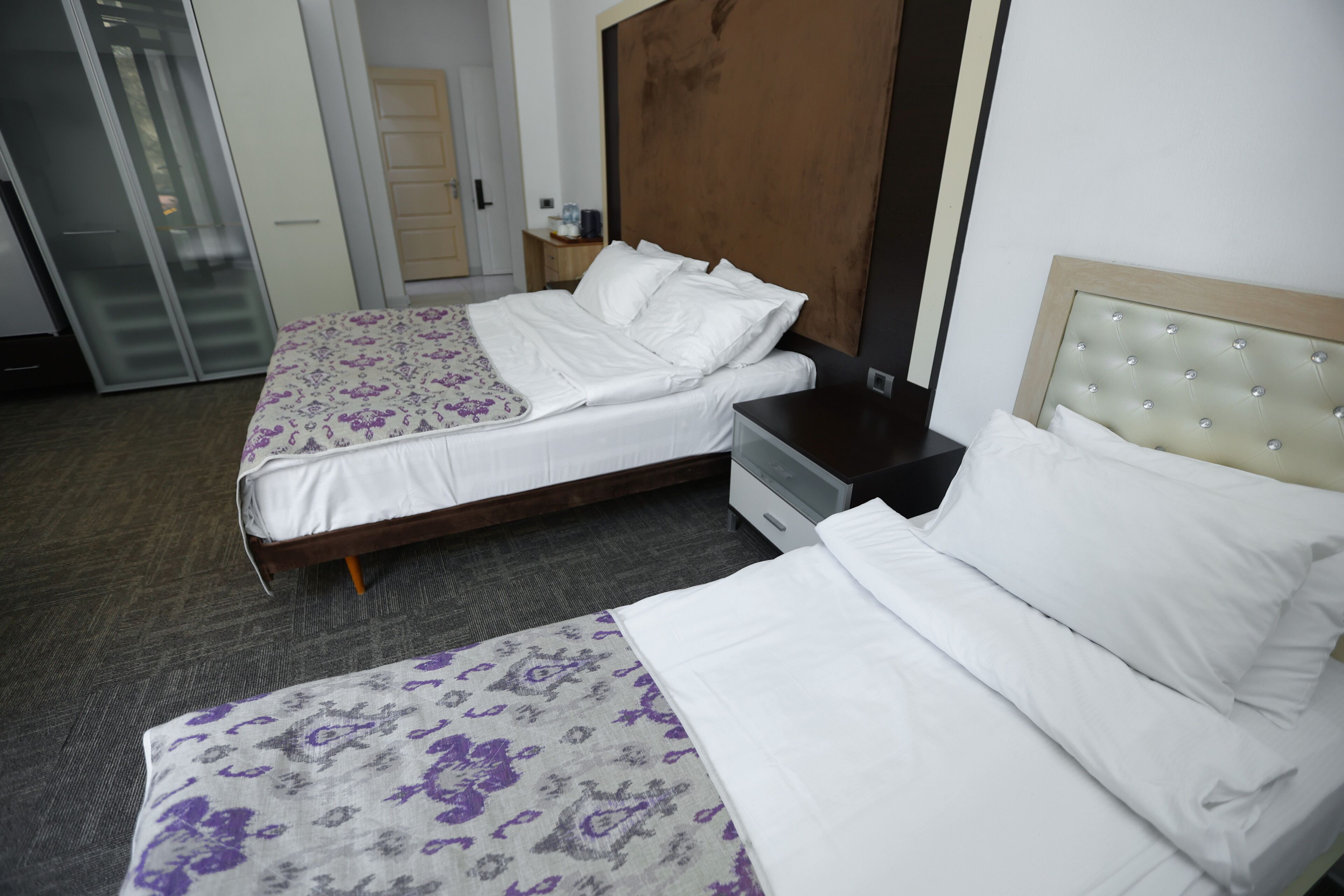Een hotelkamer met twee bedden, een kledingkast, een nachtkastje en een deur.