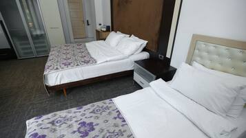 Een hotelkamer met twee bedden, een kledingkast, een nachtkastje en een deur.