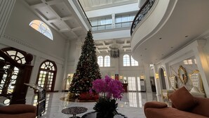 A spacious lobby with a high ceiling, a Christmas tree, and a grand staircase.