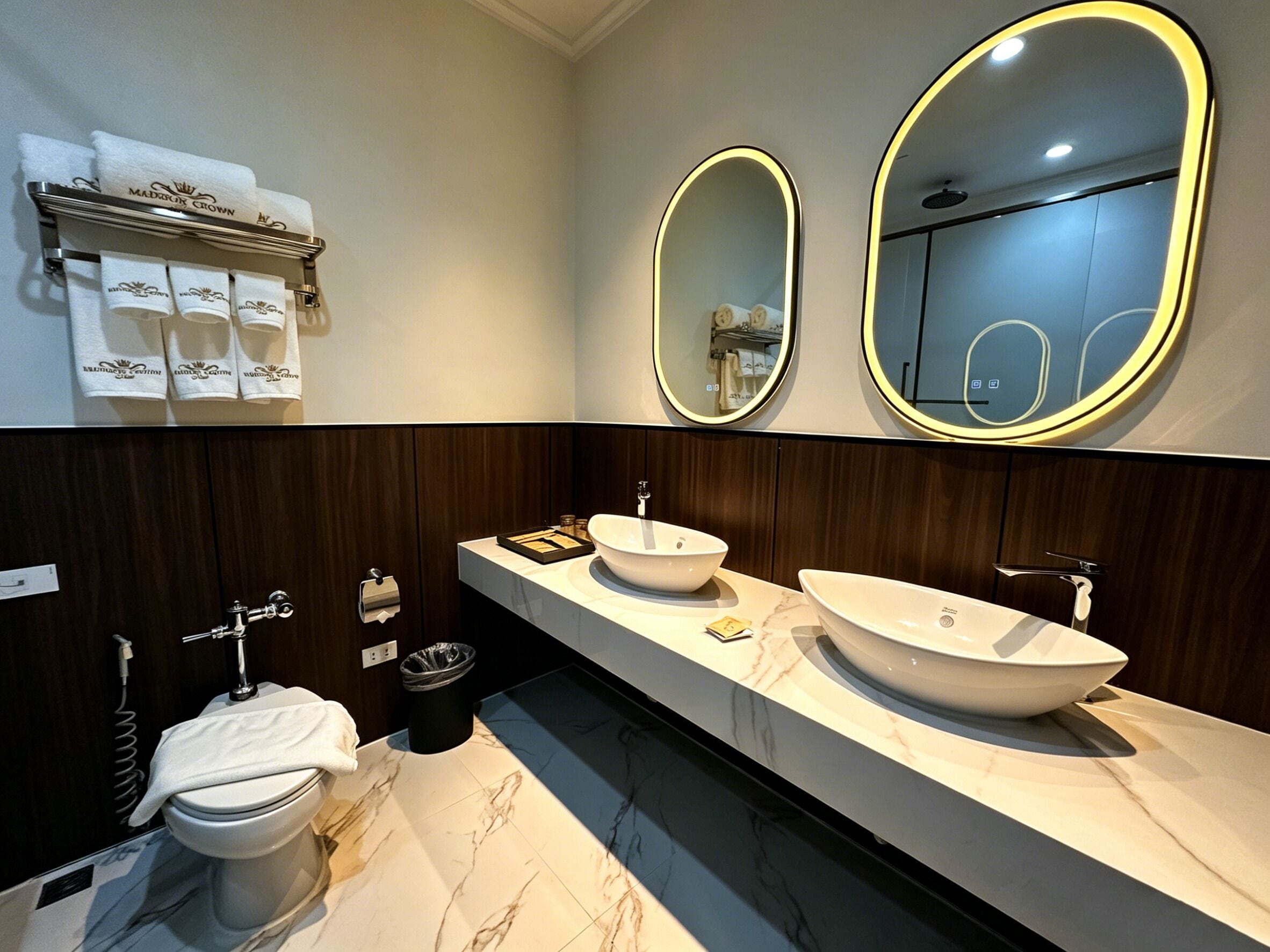 A modern bathroom with two sinks, a toilet, and a vanity with a mirror.