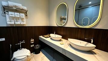 A modern bathroom with two sinks, a toilet, and a vanity with a mirror.