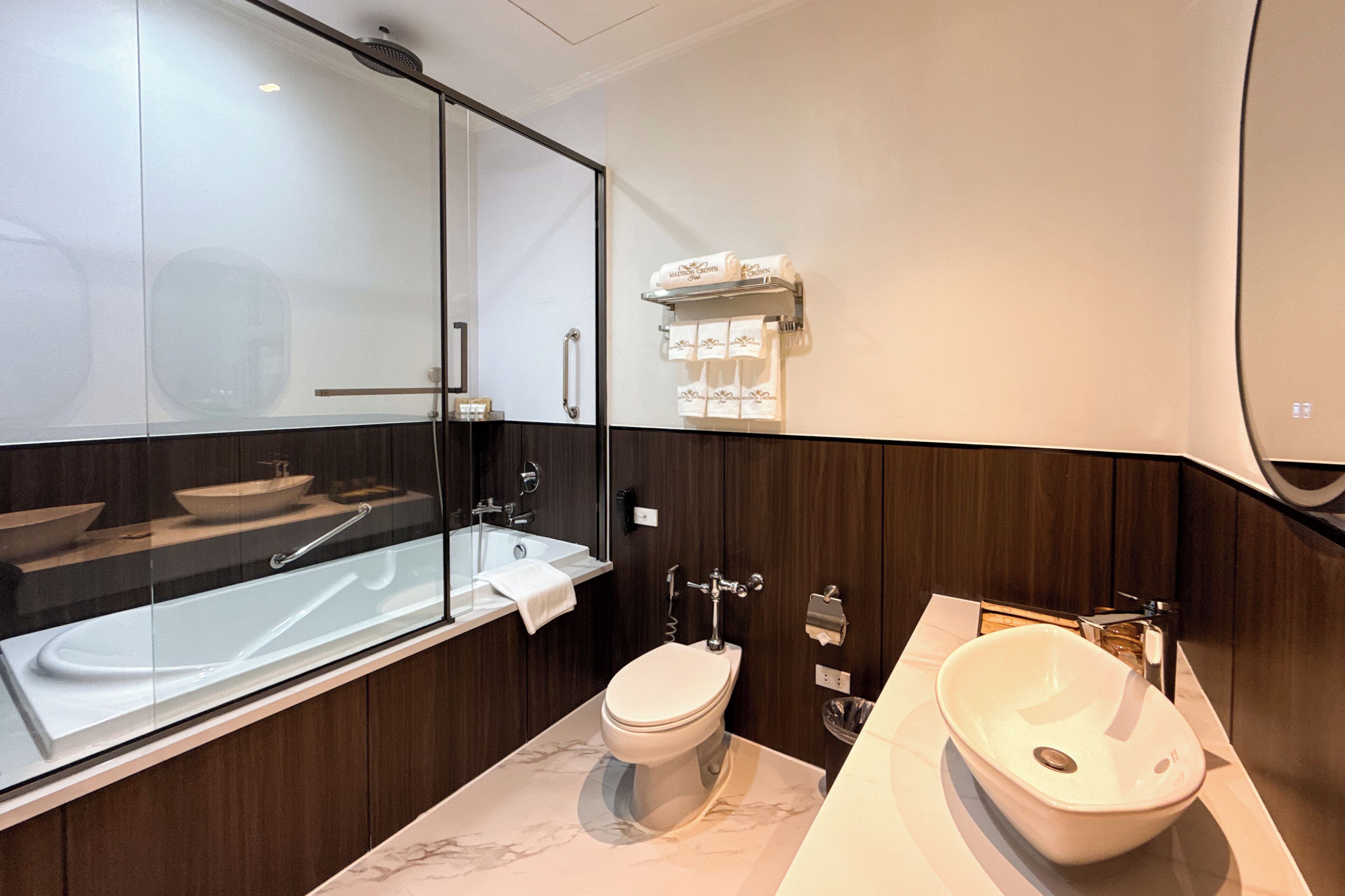 Et moderne badeværelse med et glasafskærmet brusebad, badekar, toilet og vask.