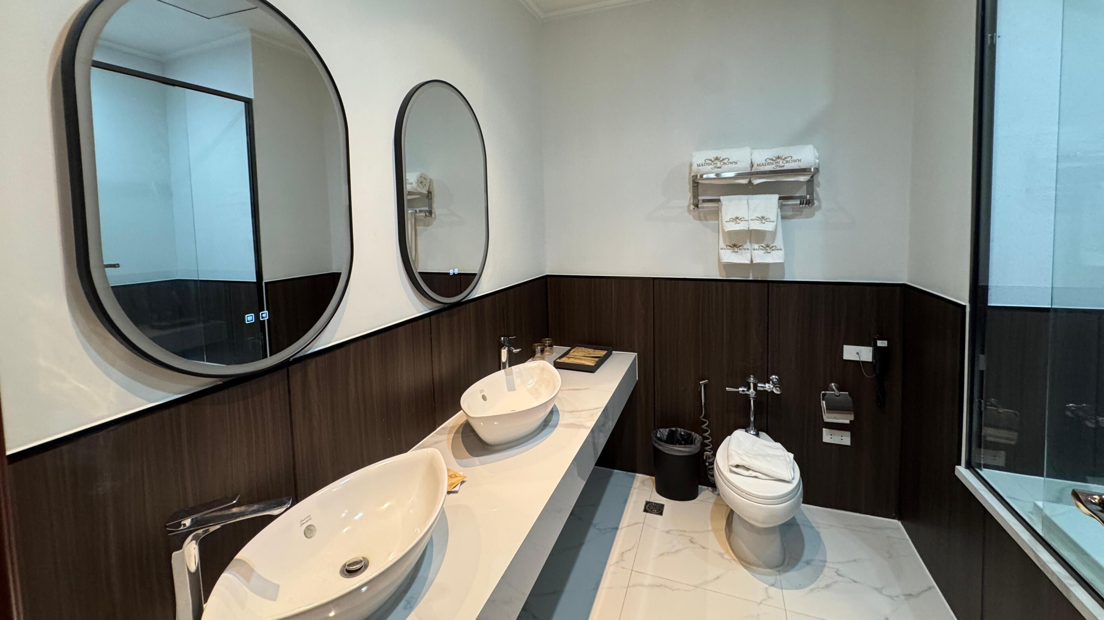 A modern bathroom with two sinks, a toilet, and two large mirrors.