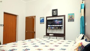Un dormitorio con una cama, un televisor montado en la pared y dos puertas.