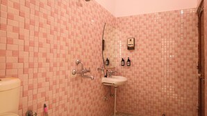 Un baño con paredes de azulejos rosas, un lavabo blanco y una ducha.