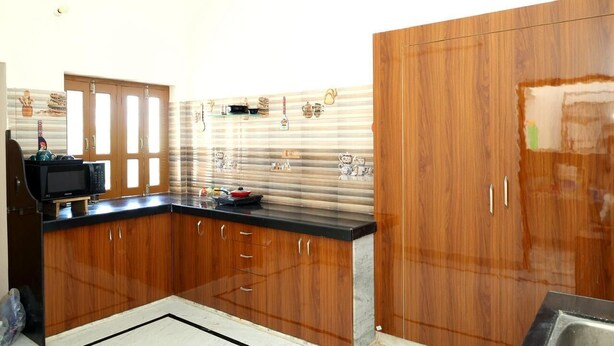 Una cocina con armarios de madera, una encimera negra y un microondas.