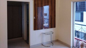 A modern interior with a wooden accent wall, a glass table, and a view of the outside. - SAS SERVICE APPARTMENT (Bengaluru)