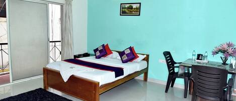 A bedroom with a bed, a desk, and a chair.