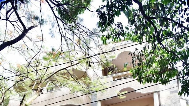 A multi-story building with balconies, a car parked in front, and dense foliage. - SAS SERVICE APPARTMENT (Bengaluru)