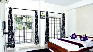 A bedroom with a bed, a TV, and a window with curtains. - SAS SERVICE APPARTMENT (Bengaluru)