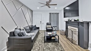 Un salon moderne avec un canapé, une table basse, une cheminée et un téléviseur fixé au mur.